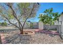 Unique drought tolerant landscaped front yard featuring decorative rock, brick accents, a mature tree and perimeter fencing with a gate at 4807 Sacks Dr, Las Vegas, NV 89122