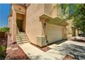 View of a two-story home featuring a two-car garage, stairs to front door, and mature landscaping at 5220 Melbourne Ridge Ct, Las Vegas, NV 89141