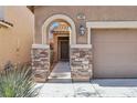 Close-up of home's entrance, showcasing stone accents, arched doorway, and well-maintained landscaping at 7407 Bakewell Ave, Las Vegas, NV 89179