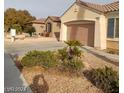 A single-story home with a two-car garage surrounded by desert landscaping at 1652 Black Fox Canyon Rd, Henderson, NV 89052