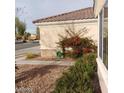 The side of a house with a garden hose, rock landscaping, and a bougainvillea at 1652 Black Fox Canyon Rd, Henderson, NV 89052