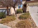 Home's front yard with minimal desert landscaping, including gravel, bushes, and a small tree at 256 Camino Viejo St, Henderson, NV 89012
