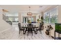 Elegant dining room featuring marble floors, modern chandelier, a view of the living room, and large windows at 2608 Prospector Mine Ave, North Las Vegas, NV 89031