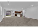 Open floor plan with carpeted living room and kitchen with stainless steel appliances at 5677 Asyma Ct, Las Vegas, NV 89113