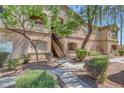 Tan two story condo with trimmed bushes and trees and stairway to upper units at 5751 E Hacienda Ave # 159, Las Vegas, NV 89122