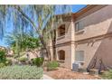 Tan two story condo with trimmed bushes and trees and stairway to upper units at 5751 E Hacienda Ave # 159, Las Vegas, NV 89122