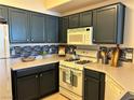 Well-equipped kitchen with white appliances, dark cabinets, and a stylish backsplash at 5855 Valley Dr # 2092, North Las Vegas, NV 89031