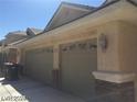 Two car garage with painted doors, stone veneer accents, decorative lights, and street number at 6245 Hawthorn Woods Ave, Las Vegas, NV 89130