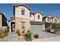 Charming two-story home with stone accents, desert landscaping, a gray two-car garage door, and a paver driveway at 6486 Vanhoven Crest St, Las Vegas, NV 89166