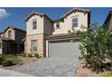 Charming two-story home with stone accents, desert landscaping, a gray two-car garage door, and a paver driveway at 6486 Vanhoven Crest St, Las Vegas, NV 89166