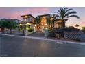 Beautiful home with an arched entryway, steps to the front door, professionally landscaped front yard and palm trees at dusk at 761 Romano Ln, Henderson, NV 89012