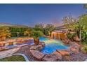 The beautiful custom pool has a rock waterfall feature and lush tropical landscaping at 10300 Wellside Hill Ave, Las Vegas, NV 89145