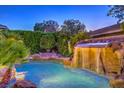Gorgeous backyard pool features a rock waterfall feature and tropical landscaping for serene relaxation at 10300 Wellside Hill Ave, Las Vegas, NV 89145