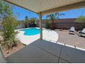 Backyard patio with pool view, featuring a covered area and chairs for outdoor relaxation at 13 Desert Dawn Ln, Henderson, NV 89074