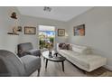 Comfortable living room with a white couch, soft chairs and natural light from the window at 15 Imposing Knoll Ave, Henderson, NV 89002