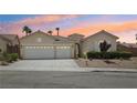 Charming home featuring a three-car garage and desert landscaping at sunset at 2297 Aria Dr, Henderson, NV 89052