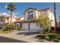 Charming two-story home featuring a three-car garage, stone accents, and desert landscaping at 323 Harpers Ferry Ave, Las Vegas, NV 89148