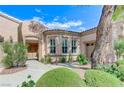 Stunning front entrance with beautiful archways, manicured landscaping, and decorative details at 4636 Riva De Romanza St, Las Vegas, NV 89135
