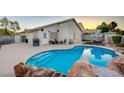 Backyard oasis showcasing a sparkling pool with rock features, a patio area, and ample space for outdoor relaxation at 528 Lavina Ct, Las Vegas, NV 89123