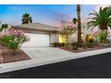 Charming single Gathering home with a well-manicured lawn, colorful flowers, and two-car garage at 7701 Sea Cliff Way, Las Vegas, NV 89128