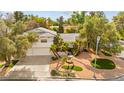 Exterior view showcases the front of the house, with a two-car garage, attractive landscaping, and mature trees at 226 Dalmatian Ln, Las Vegas, NV 89107