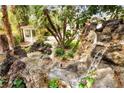 Backyard water feature with rock formations, a small waterfall, and surrounding greenery, adding to the landscape at 226 Dalmatian Ln, Las Vegas, NV 89107
