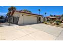 Low angle shot of a single story home with a stucco exterior, large driveway and desert landscaping at 3063 Chapala Dr, Las Vegas, NV 89120