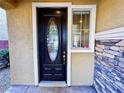 Elegant front door with decorative glass and sidelight window complements the exterior's stonework and paint at 5361 Candlespice Way, Las Vegas, NV 89135