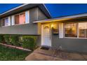 Welcoming front entrance with a classic door, neatly trimmed bushes, and an inviting glow at 6213 Fairwood Ave, Las Vegas, NV 89107