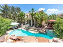 Resort-style backyard featuring a stunning pool with rock accents, lush landscaping, and seating areas at 179 Adomeit Dr, Henderson, NV 89074