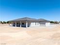 Rear exterior of a single story home with large patio and neutral color palette at 1800 Huckleberry St, Pahrump, NV 89048