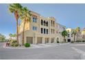 Exterior view of a multi-story building with garages and lush palm trees in a condo community at 2555 Hampton Rd # 5104, Henderson, NV 89052