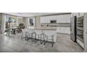 Bright kitchen featuring white cabinets, a large center island with seating, stainless steel appliances, and open dining area at 3195 Hazy Hills Ave, Henderson, NV 89052