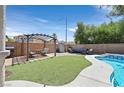 Relaxing backyard oasis with a pergola, artificial grass, and a sparkling pool, creating a perfect outdoor retreat at 3591 Gloucester Gate St, Las Vegas, NV 89122
