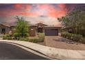 Exterior view of a single-story home with lush landscaping and a brick driveway during sunset at 368 Calabria Beach St, Henderson, NV 89015
