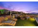 Relaxing rooftop deck area featuring comfortable lounge chairs, an outdoor kitchen, and stunning mountain views at 5 Highland Cove Ln, Henderson, NV 89011