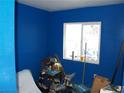 Small, blue bedroom with a window and various boxes and clutter on the floor at 5068 Killarney St, Las Vegas, NV 89122