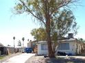 Exterior shot of a single-story home featuring light siding and a front yard with mature trees at 5068 Killarney St, Las Vegas, NV 89122