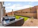 Private backyard featuring artificial grass, rock landscaping and a cozy seating area with a fire table at 7211 Alabaster Peak St, Las Vegas, NV 89166