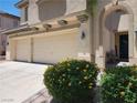 Tan home featuring a three-car garage, desert landscaping, and an arched entry way at 9052 Pine Mission Ave, Las Vegas, NV 89143