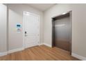 Hallway featuring a white entry door with a stainless steel elevator on wood flooring at 128 Los Cabos Dr # 202, Las Vegas, NV 89144