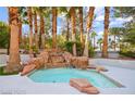 Tranquil backyard pool with an eye-catching rock waterfall feature and mature palm trees at 2608 Sun Reef Rd, Las Vegas, NV 89128