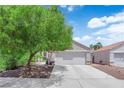 View of a well-manicured front yard and a two-car garage at 5228 Harmony Ave, Las Vegas, NV 89107
