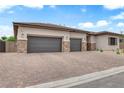 Exterior view of a home featuring a three-car garage and desert-style landscaping at 5851 Slate Rock Ct, Las Vegas, NV 89149
