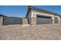 A long three-car garage with stone accents, automatic black garage doors, and a matching gate, perfect for car enthusiasts at 5851 Slate Rock Ct, Las Vegas, NV 89149