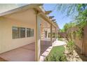 Backyard with covered patio, privacy wall, small section of green space and sparse desert landscaping at 7263 Pepperbox Ave, Las Vegas, NV 89179