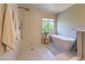 Serene bathroom featuring a freestanding tub, a walk-in shower, and elegant marble-style tiles at 8221 Ebony Peak St, Las Vegas, NV 89143