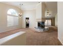 Open living room has high ceilings, fireplace, large windows, and neutral carpet at 902 Possum Hill St, Henderson, NV 89014