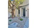 Landscaped front yard with decorative rock features, plants, and a mature shade tree at 908 Shining Rose Pl, Henderson, NV 89052