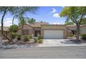 Inviting single-story home with a two-car garage, desert landscaping, and a tiled roof at 10017 Bundella Dr, Las Vegas, NV 89134